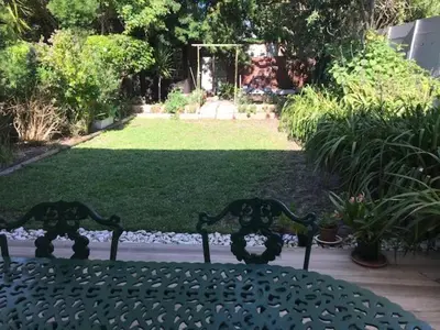 a green bench sitting in front of a garden at At 27 on Derby in Cape Town