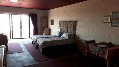 a bedroom with a bed and a large window at Jack's Seaview in Bettyʼs Bay