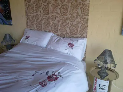 a bed with white sheets and red flowers on it at Jack's Seaview in Bettyʼs Bay