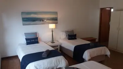a room with two beds and a lamp in it at Arbeidsgenot Beach House in Hermanus