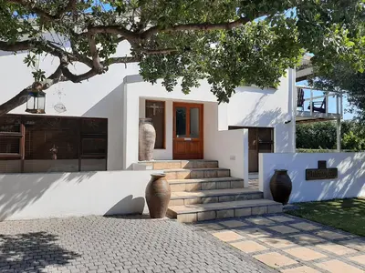 a white house with stairs and a tree at Arbeidsgenot Beach House in Hermanus