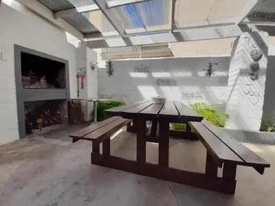 a picnic table in a patio with a fireplace at Arbeidsgenot Beach House in Hermanus