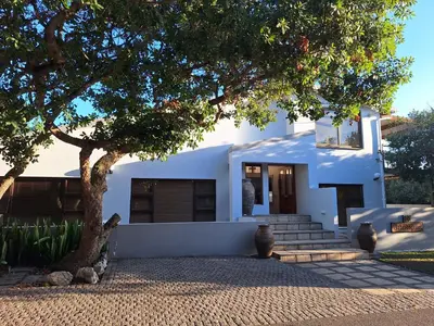 a white house with a tree in front of it at Arbeidsgenot Beach House in Hermanus