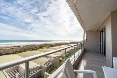 a balcony with a view of the beach at Luxury Private Beachfront 2 bedroom Dolphin Apartment, Blouberg, Cape Town in Bloubergstrand