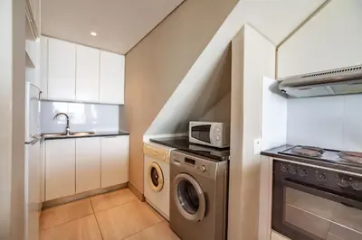 a kitchen with a washing machine and a microwave at Luxury Private Beachfront 2 bedroom Dolphin Apartment, Blouberg, Cape Town in Bloubergstrand