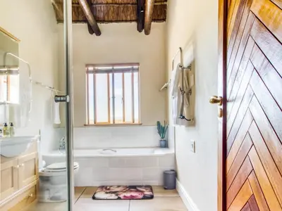 a bathroom with a tub and a toilet and a door at Lord's Wine Farm in McGregor