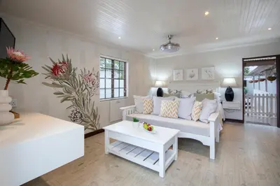 a living room with a white couch and a table at The Potting Shed Guest House in Hermanus
