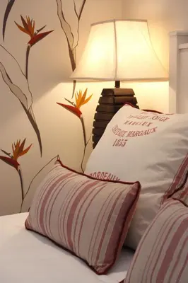a bedroom with a bed with a lamp and flowers on the wall at The Potting Shed Guest House in Hermanus
