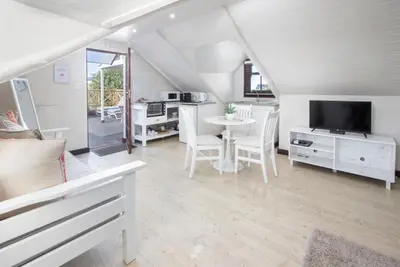 a living room with a table and a tv at The Potting Shed Guest House in Hermanus