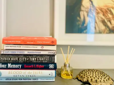a stack of books sitting on a table with a seashell at Milnerton Cottage in Cape Town