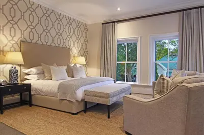a bedroom with a bed and a chair and windows at Stellenbosch Manor in Stellenbosch