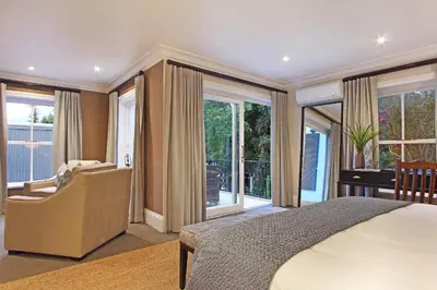 a bedroom with a bed and a chair and windows at Stellenbosch Manor in Stellenbosch