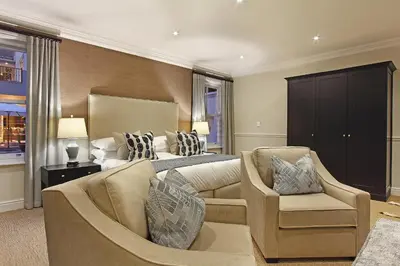 a bedroom with a bed and a couch and chairs at Stellenbosch Manor in Stellenbosch