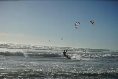 two people kite surfing on the waves in the ocean at Peak Village Lodge in Bloubergstrand