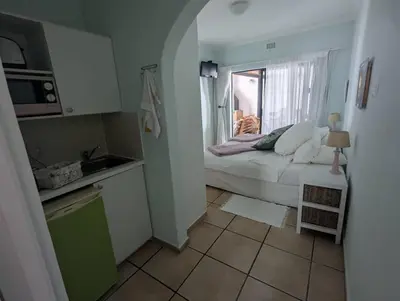 a small kitchen with a bed and a window at Peak Village Lodge in Bloubergstrand