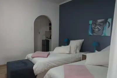 two beds in a room with a painting on the wall at Peak Village Lodge in Bloubergstrand