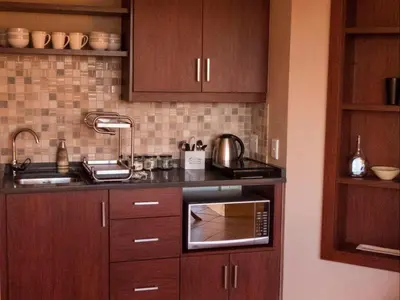 a kitchen with wooden cabinets and a stove top oven at Ville la'Rina in Cape Town