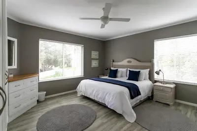 a bedroom with a bed and two windows and a ceiling fan at Son & Saffier in Hermanus
