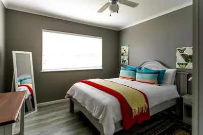 a bedroom with a bed with blue pillows and a window at Son & Saffier in Hermanus