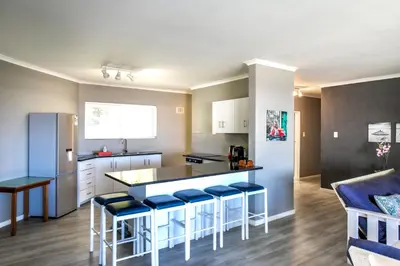 a kitchen with a counter and some blue stools at Son & Saffier in Hermanus