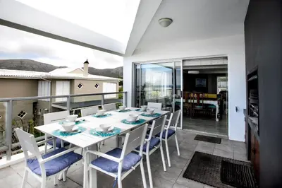 a dining room with a table and chairs on a balcony at Son & Saffier in Hermanus