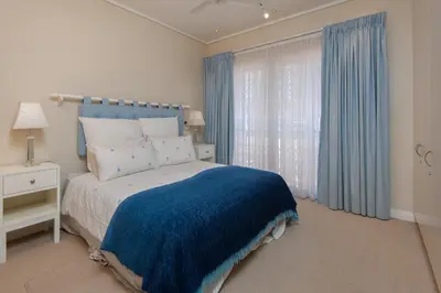 a bedroom with a blue and white bed and a window at Bietou on the Sea in Hermanus