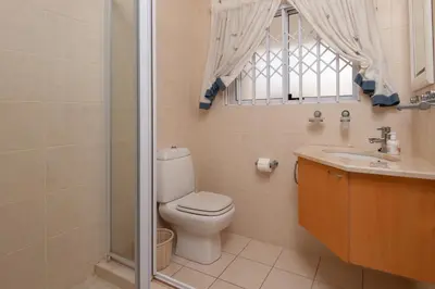 a bathroom with a toilet and a sink and a window at Bietou on the Sea in Hermanus
