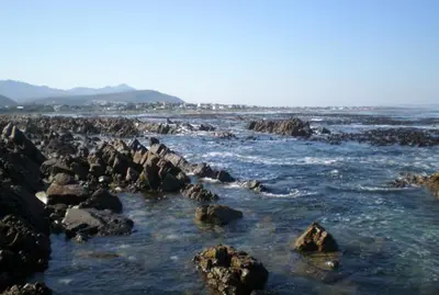 a group of rocks in the water on a beach at Bietou on the Sea in Hermanus