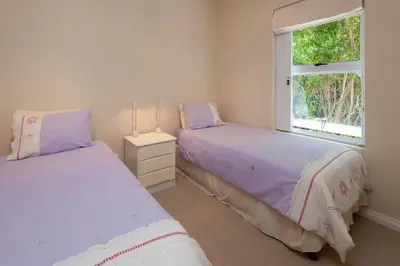 two beds in a room with a window at Bietou on the Sea in Hermanus