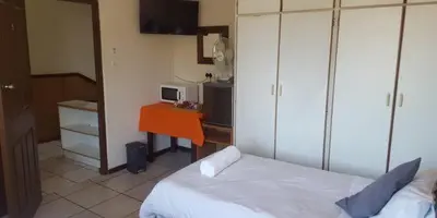 a bedroom with a bed and a desk with a microwave at Lodge Strand (The) in Strand