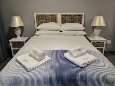 a bed with towels on top of it with two lamps at Northern Vine Guesthouse B&B Self-catering in Brackenfell