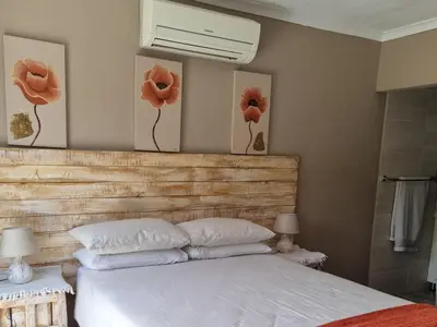 a bedroom with a bed with red flowers on the wall at Northern Vine Guesthouse B&B Self-catering in Brackenfell