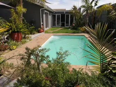 a swimming pool in front of a house with plants at Northern Vine Guesthouse B&B Self-catering in Brackenfell