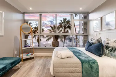 a bedroom with a bed and a large window at Ashley on Beach Strand in Strand