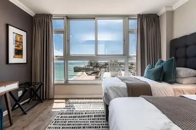 a bedroom with two beds and a large window at Ashley on Beach Strand in Strand