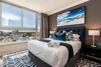 a bedroom with a large bed with a large window at Ashley on Beach Strand in Strand