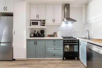 a kitchen with blue cabinets and a stove top oven at Ashley on Beach Strand in Strand