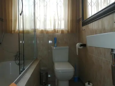 a bathroom with a toilet and a shower and a sink at Onyx on Sycamore in Cape Town