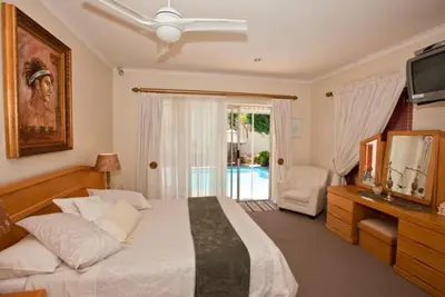 a bedroom with a bed and a television and a chair at Annette Guesthouse in Plattekloof