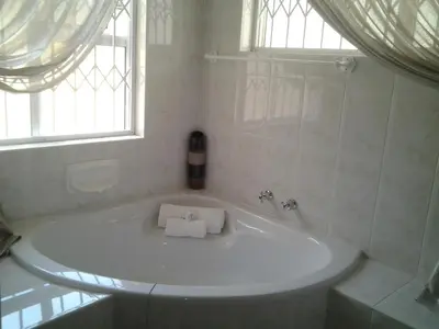 a white bath tub in a bathroom with a window at Annette Guesthouse in Plattekloof