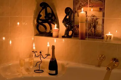 a bottle of champagne sitting on a bathroom sink with candles at Annette Guesthouse in Plattekloof