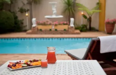 a tray of fruit and juice on a table next to a pool at Annette Guesthouse in Plattekloof