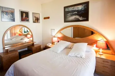 a bedroom with a large white bed and a mirror at Annette Guesthouse in Plattekloof