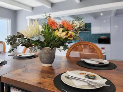 a wooden table with a vase of flowers on it at Salt Boutique Guest House in Bloubergstrand