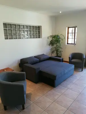 a living room with a blue bed and two chairs at Coons Cove in Cape Town