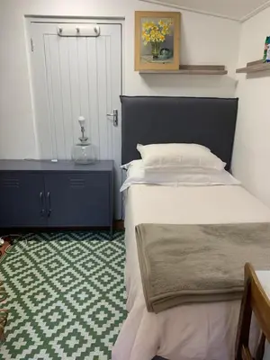 a bedroom with a bed and a table and a door at Just a Bed parking on street in Stellenbosch