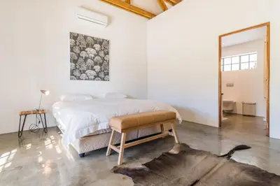 a white bedroom with a bed and a mirror at Druk My Niet Wine Estate in Paarl
