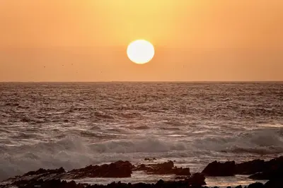 a sunset over the ocean with the sun setting at Whales & Waves in Hermanus
