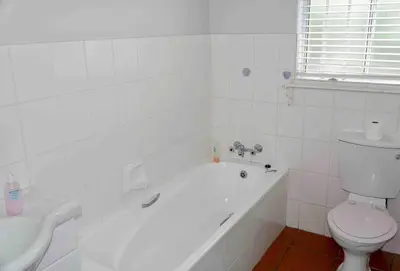 a bathroom with a tub and a toilet and a sink at Whales & Waves in Hermanus