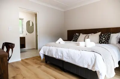 a bedroom with a large bed with white sheets at Skinkikofi Guest House in Paarl
